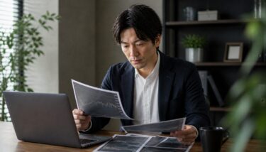 明るい作業空間で株式投資の資料とパソコンを確認する日本人投資家のリアルな写真